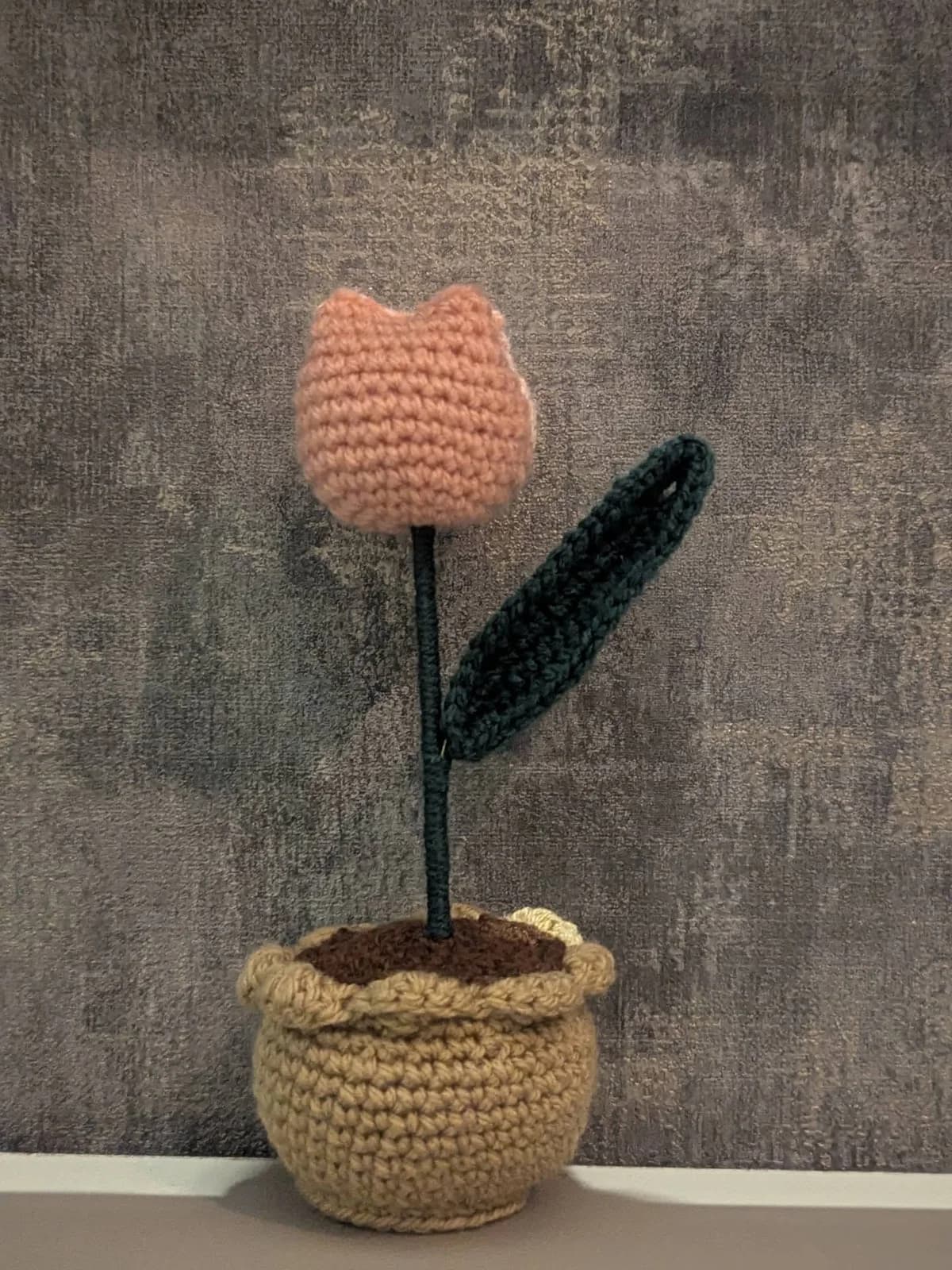 Peach crochet tulip with a green leaf in a small tan crochet pot